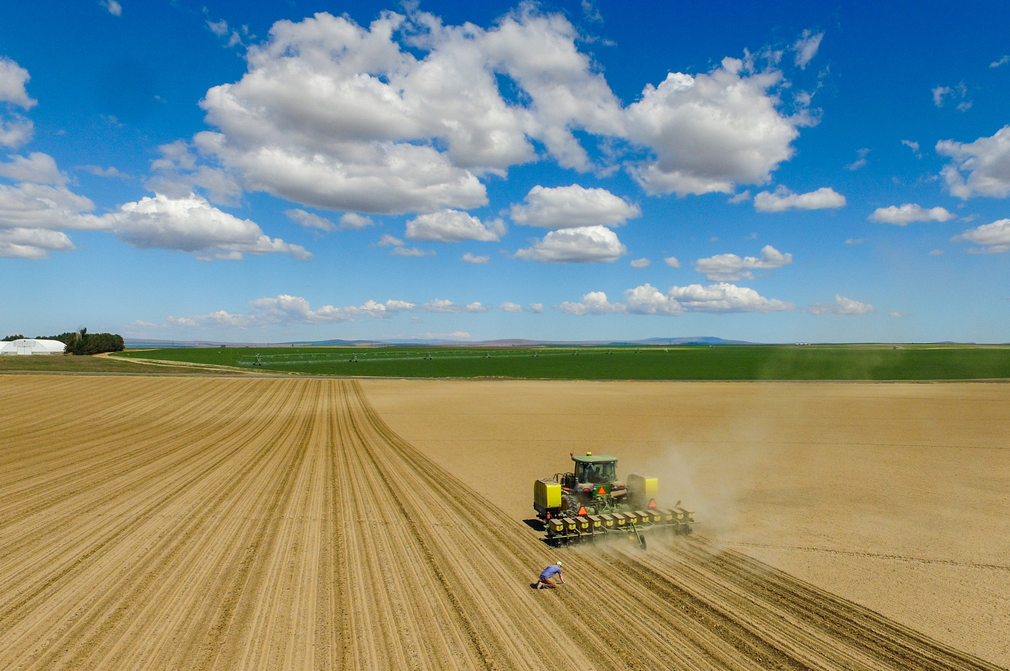 An aerial shot of a man and a tractor in a large field